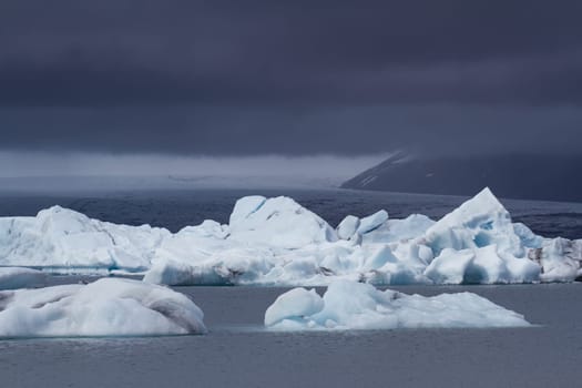 Glacier in lagoon with storm clouds above in Iceland