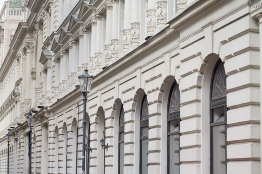 Perspective view of long classical building with windows and street lights in front