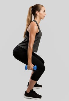 Young fitness woman making exercises with dumbbells