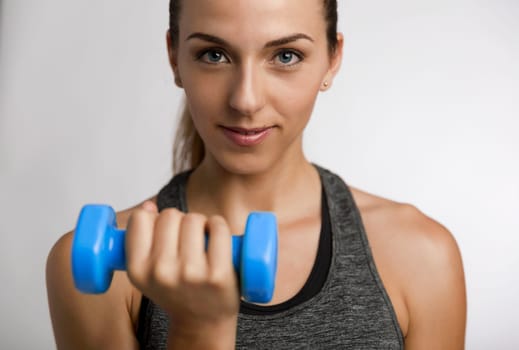 Young fitness woman making exercises with dumbbells