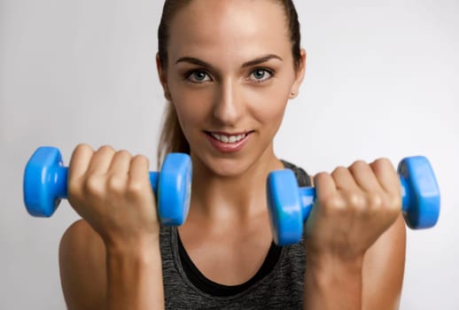 Young fitness woman making exercises with dumbbells