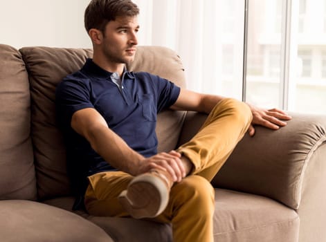 Portrait of a handsome young man sitting on the sofa