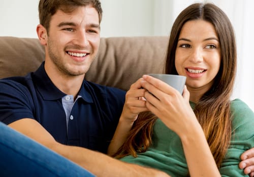 Young couple on the sofa drinking coffee