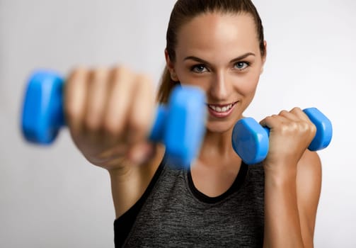 Young fitness woman making exercises with dumbbells