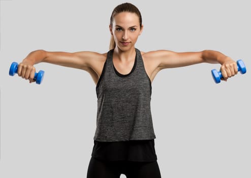 Young fitness woman making exercises with dumbbells