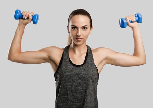 Young fitness woman making exercises with dumbbells