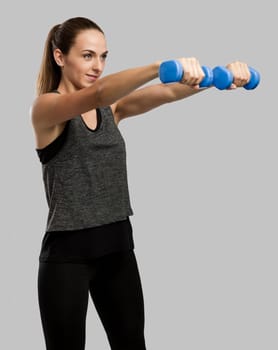 Young fitness woman making exercises with dumbbells