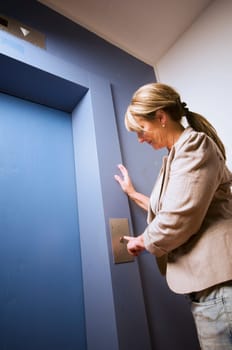 Frightened woman waits at a blue lift door.