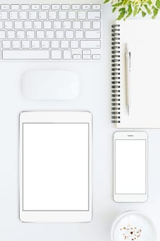 phone and tablet blank screen on white table format vertical top view