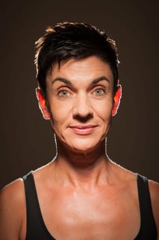 Head-and-shoulder portrait of a middle-aged black-haired woman against a black background looking into the camera in the spotlight.