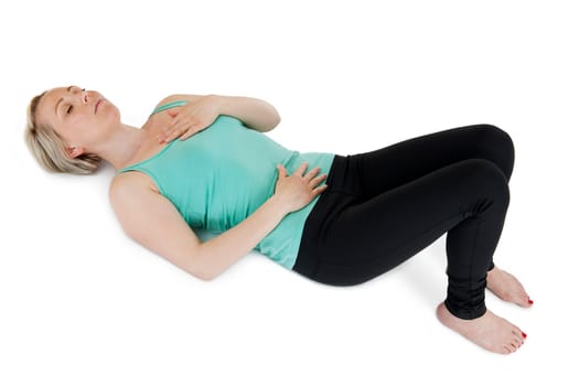 Young woman in supine position on a white background with squatted legs,closed eyes her hands placed on her stomach and chest.
