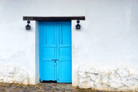 View of old wooden door on white colonial building in Villa de Leyva, Colombia