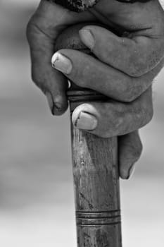 Vertical close up of an old man hand holding a wooden walking stick