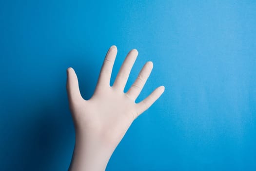 Horizontal front view of hand with surgical white glove on blue background