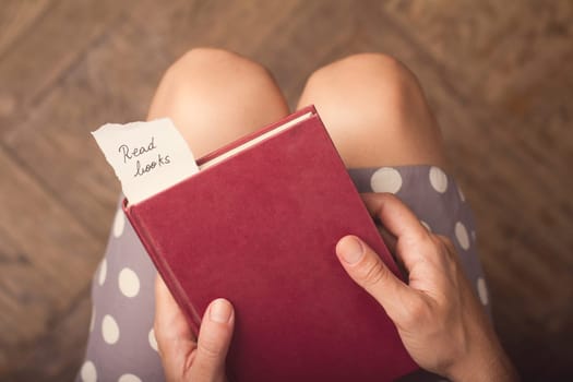 Hand holding a book with note of paper with the message read books on it