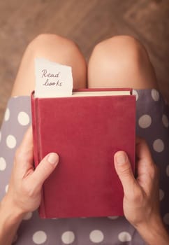 Hand holding a book with note of paper with the message read books on it