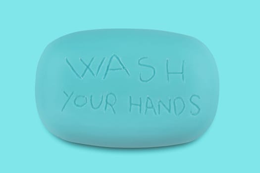 Top view of a blue soap bar with the words wash your hands scratched on it