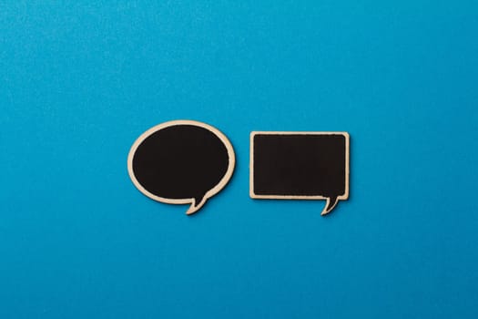 horizontal top view of charcoal wooden speech bubbles with different shapes on blue background