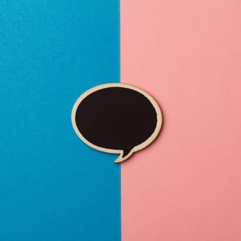 Top view of round empty chalkboard wooden speech bubble on pink and blue background