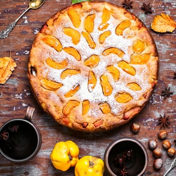 Warm aromatic tea in hand and pie with autumn quince