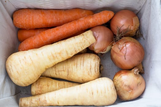 Top view of vegetable storage draw with parsnips, carrots and onions.