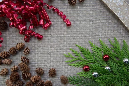 Christmas ribbons and pine cones on linen background with copy spacy
