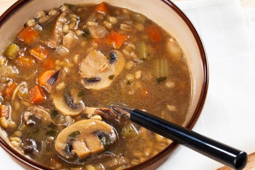 Bowl of homemade mushroom and barley soup with spoon in it ready to eat