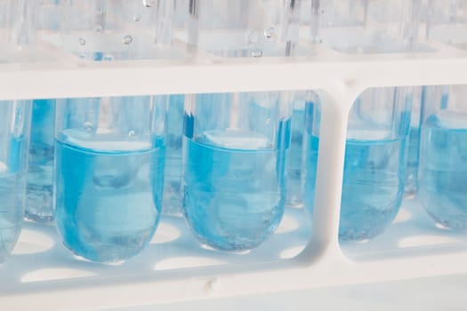Close up of test tubes in rack with blue liquid.