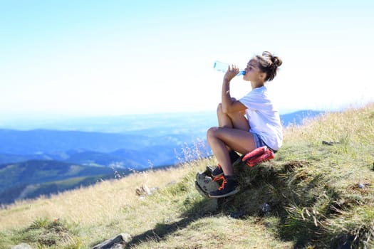 summer holidays in the mountains. the girl is drinking water.