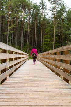 View of a hiker crossing a wooden bridge