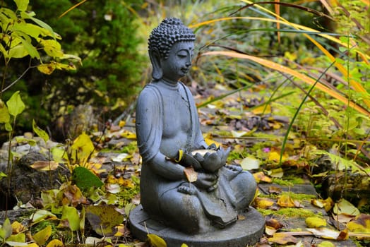 colorful autumn in the garden by a pond with a Buddha