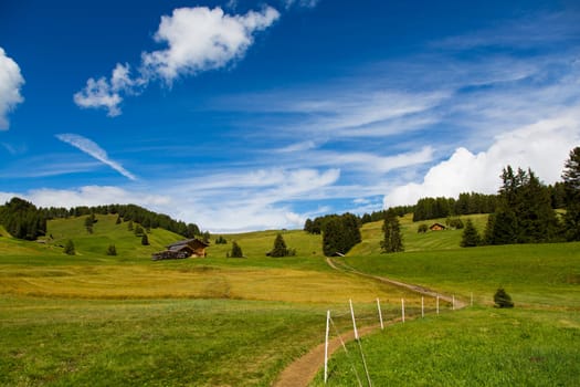 panoramic view of the Seiser Alm in a sunny day with blue sky and clouds with path in the foreground