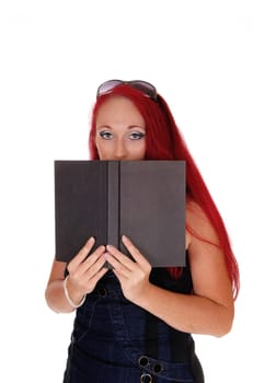A business woman holding a book on her face, standing.with long red hair isolated for white background..
