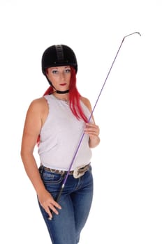 A happy woman with her rider helmet and whip, with long red hair.standing isolated for white background..