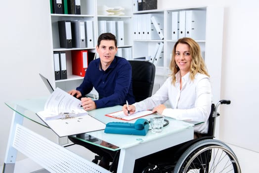 disabled businesswoman in wheelchair and her colleague in the office