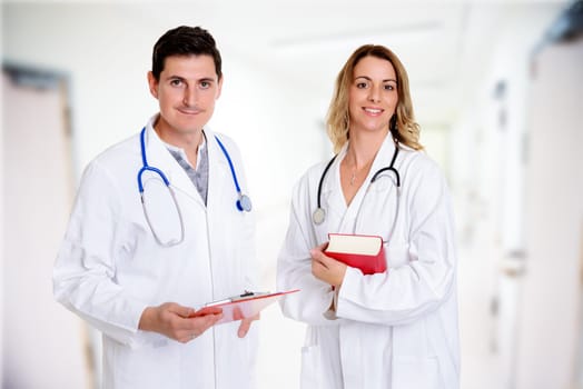 young friendly medical team with book in lab coat in front of clinic background