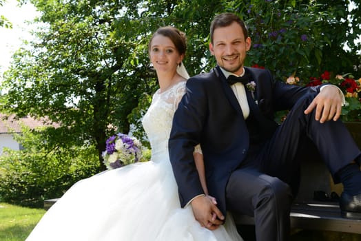 Young bridal couple sits in the park on a park bench
