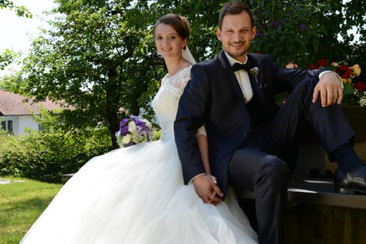 Young bridal couple sits in the park on a park bench