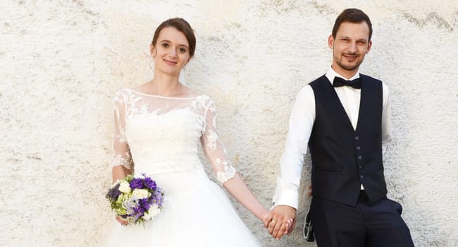 Happy young bridal couple in front of an old house wall