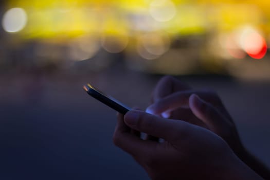 close-up hand use phone on night time in the city