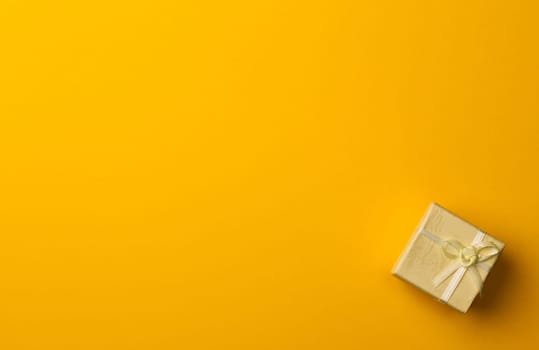horizontal top view of gift box on minimal yellow background paper textures