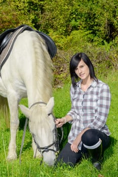 young rider  brunette girl with her white horse