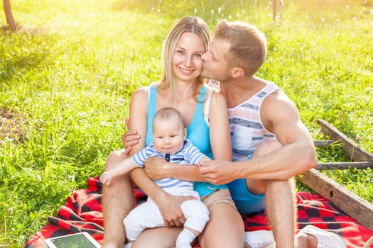 Happy family enjoying a picnic with their baby outdoors