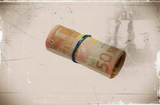 A roll with fifty Euro banknotes on a sepia background