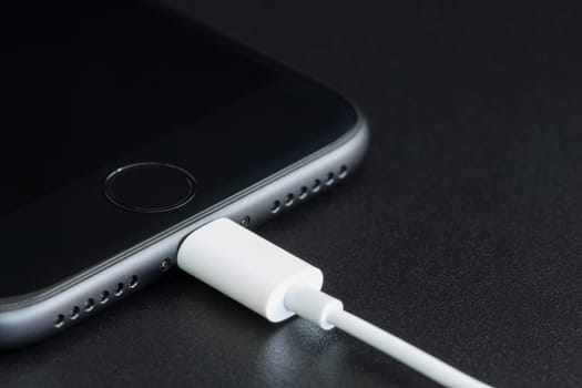 Bangkok, Thailand - November 2, 2016: Close-up iPhone 7 matte black connect to usb cable, new iPhone 7 is manufactured by apple inc.