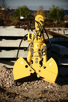 The close-up of an excavator shovel next to tools and materials.