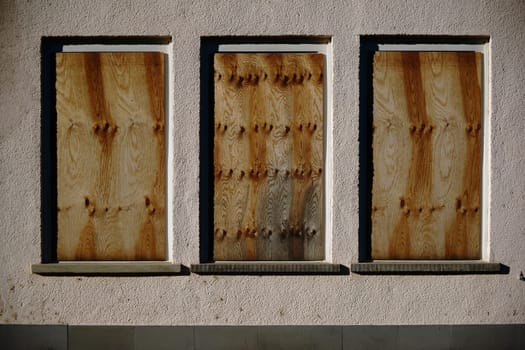 A dilapidated building with nailed windows and a yellowed façade.