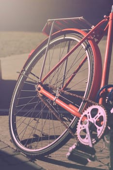Vertical close up of an orange city bike in the morning light