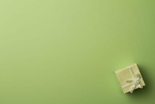 Top view small gift box with ribbon on green background with copy space