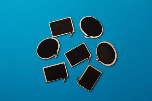 Horizontal top view of many chalkboard wooden speech bubbles on light blue background, team work concept